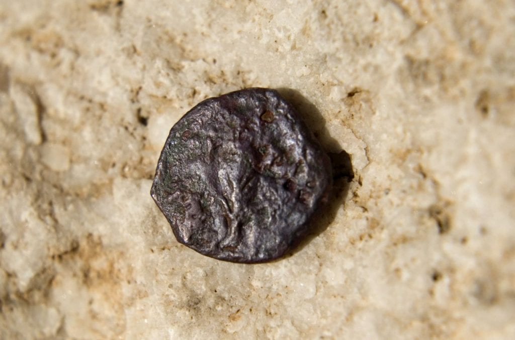 An ancient coin, one of 17 discovered in an underground part of the Western Wall, the holiest site where Jews can pray, is seen in a presentation of archeological excavations in Jerusalem's Old City, Wednesday, Nov. 23, 2011. Newly found coins underneath the Western Wall are identified as stamped by a Roman proconsul 20-years after hte death of Herod, a Jewish ruler who died in 4 B.C., and could change the accepted belief about the construction of one of the world's most sacred sites two millennia ago, Israeli archaeologists said Wednesday. (AP Photo/Sebastian Scheiner)